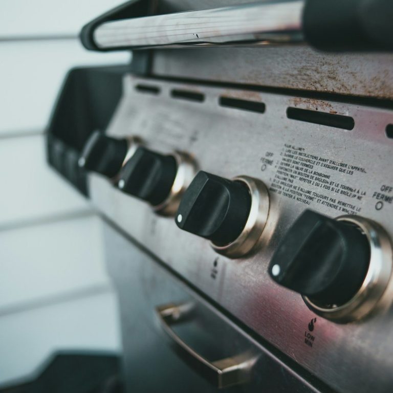 Grill mit mehreren Reglern und einer metallischen Oberfläche.