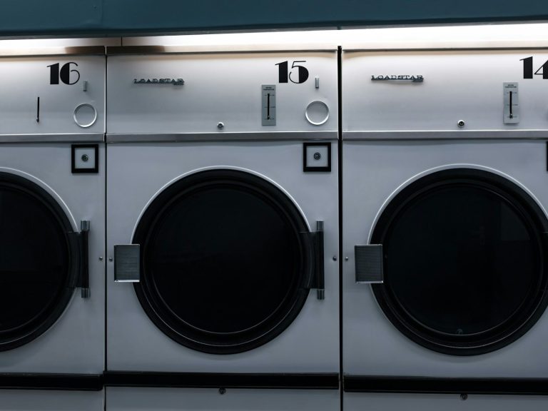 Drei Waschmaschinen mit runden Türen in einer Wäscherei.