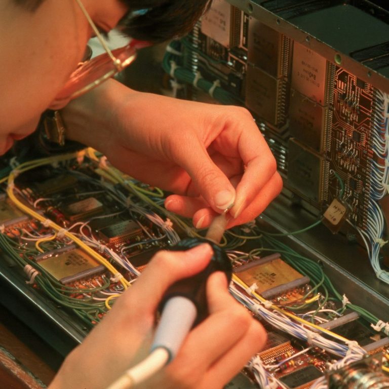 Eine Person lötet Kabel auf einer Platine in einer Mikrowelle.