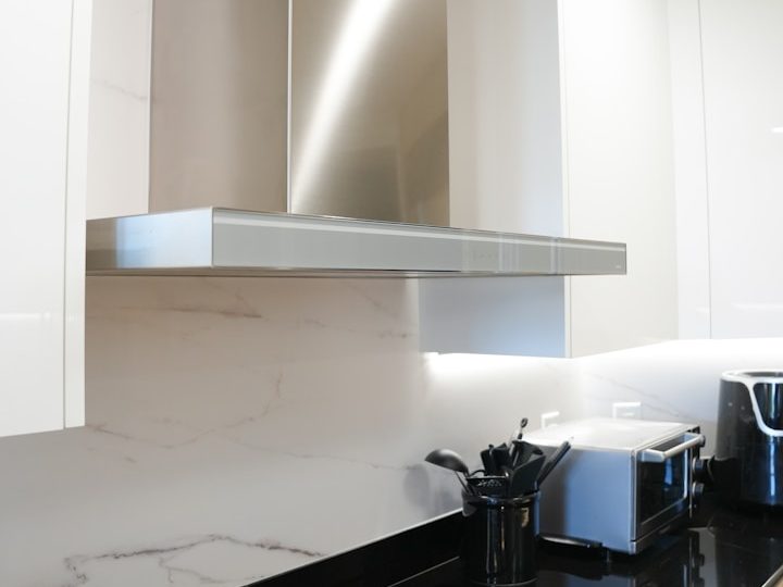 Moderne Küchenzeile mit Edelstahl-Dunstabzugshaube und geringer Abstellfläche.