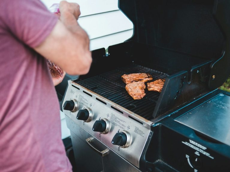 Ein Mann grillt Fleisch auf einem Gasgrill im Freien.