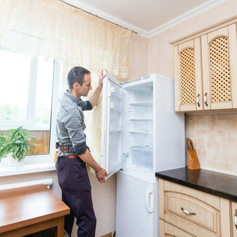 Mann öffnet einen Kühlschrank in einer modernen Küche mit Holzschränken.