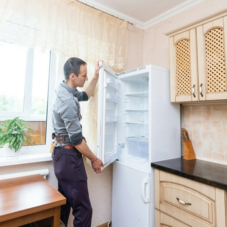 Mann öffnet Kühlschrank in einer modernen Küche mit Holzregalen.