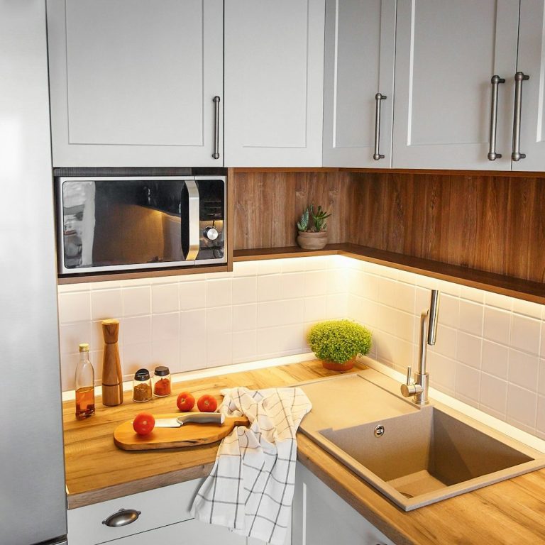 Moderne Küche mit Holzarbeitsplatte, Spüle, Mikrowelle und frischen Zutaten.