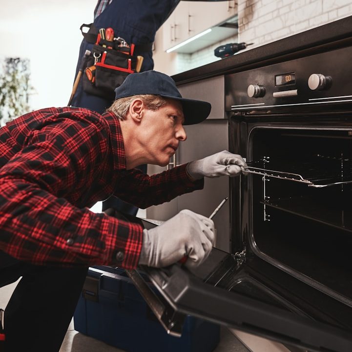 Ein Techniker repariert einen Ofen in einer modernen Küche.